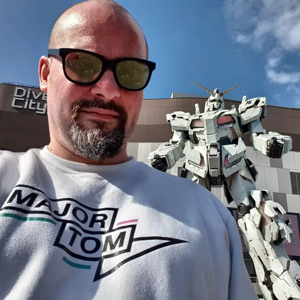 Yann in a Major Tom sweater in front of the life-size Gundam robot statue at DiverCity Tokyo