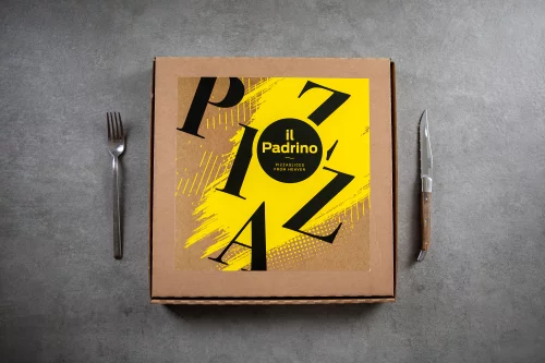 A yellow Il Padrino pizza box with big black letters, between a fork and a knife