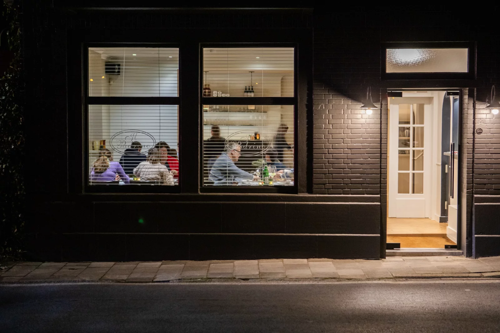 The front of Il Padrino in Lovendegem at night, with the windows lit