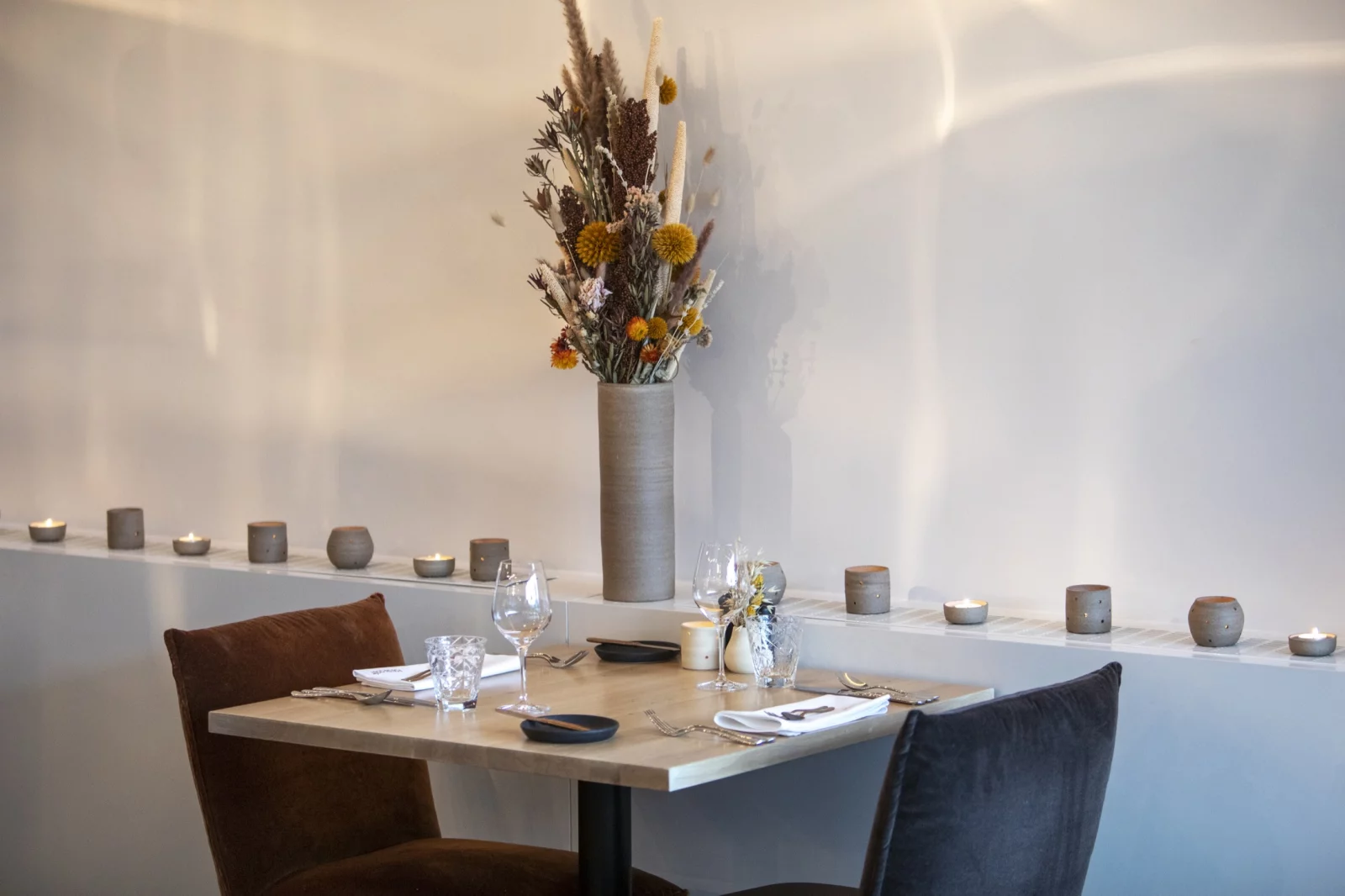 A set table in the dining room of Fou du Go&ucirc;t, with candles and dried flowers