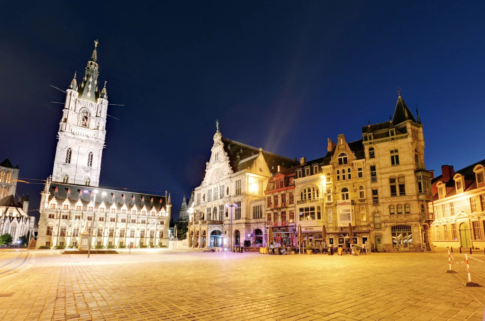 Het Sint-Baafsplein in Gent bij avond, met het verlichte Belfort en de gevels rond het plein