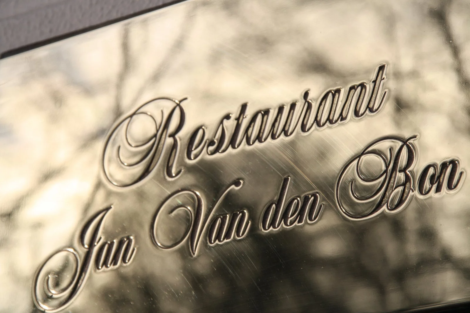 Engraved brass sign reading &ldquo;Restaurant Jan Van den Bon&rdquo; on the facade