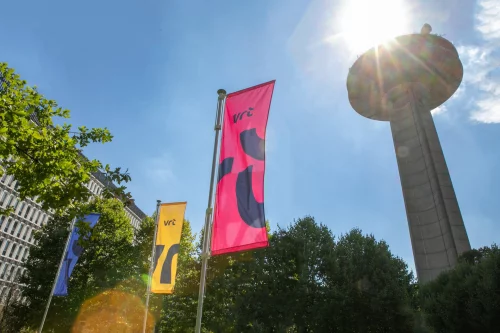 VRT flags in the sun, with the broadcasting tower behind them