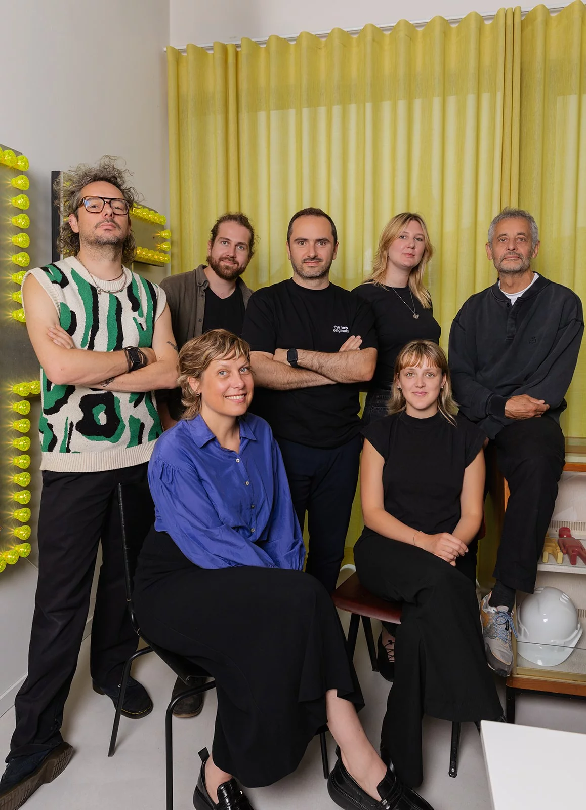 Het team van Pi&egrave;ce Mont&eacute;e in hun studio in Gentbrugge, voor een wand met gele lichtletters
