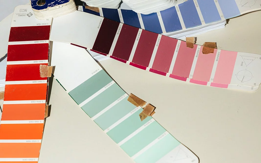 Colour swatches in red, orange, burgundy, pink, mint and blue on a table in the Pi&egrave;ce Mont&eacute;e studio
