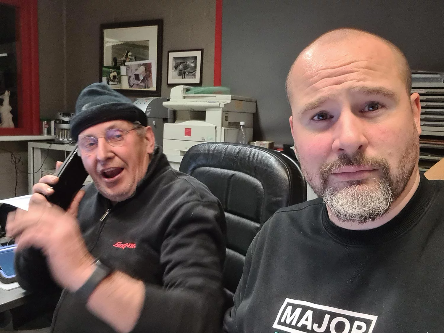 Mr De Coninck in a beanie, on the phone at his desk, next to Yann from Major Tom