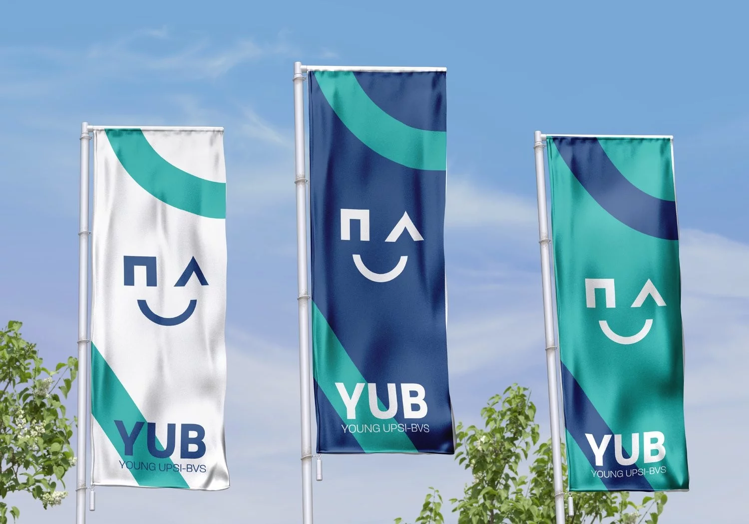 Drie vlaggen van YUB, Young UPSI-BVS, in wit, blauw en mint tegen een blauwe lucht